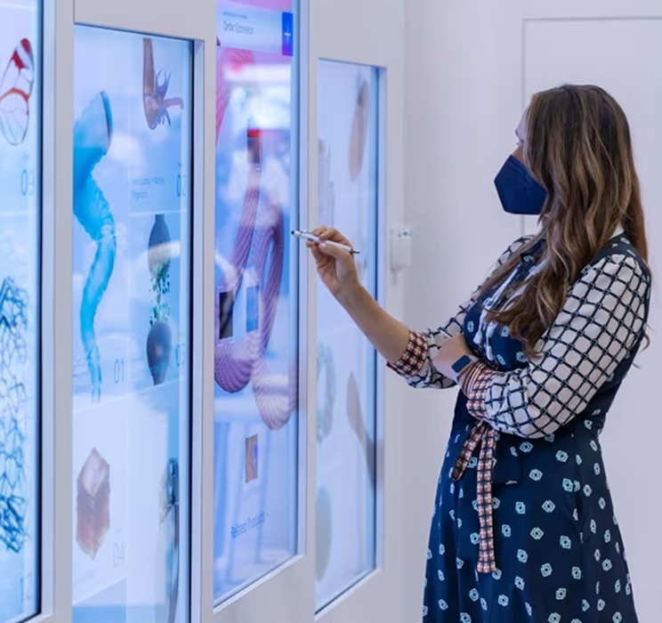 Womn in mask using a touch-screen panel to inspect microscopic images