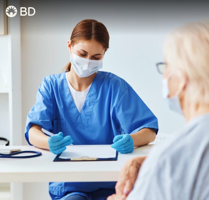woman in scrubs and mark writing on clipboard, patient in foreground
