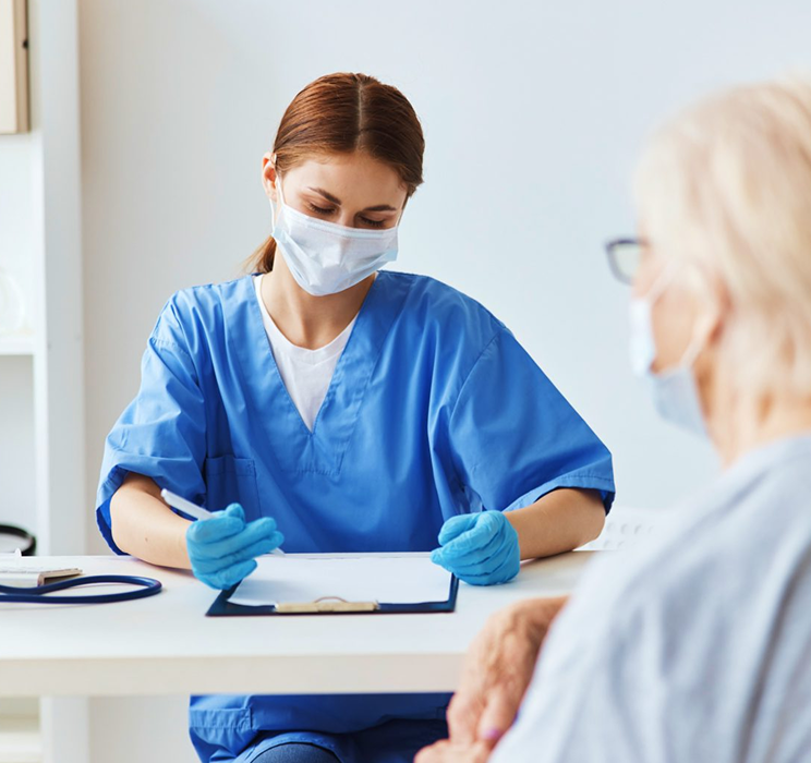 woman in scrubs and mark writing on clipboard, patient in foreground